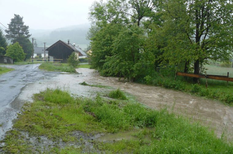 Rozvodněný Dešenický potok právě opustil Husí plácek a míří k bytovkám a do Milenců
